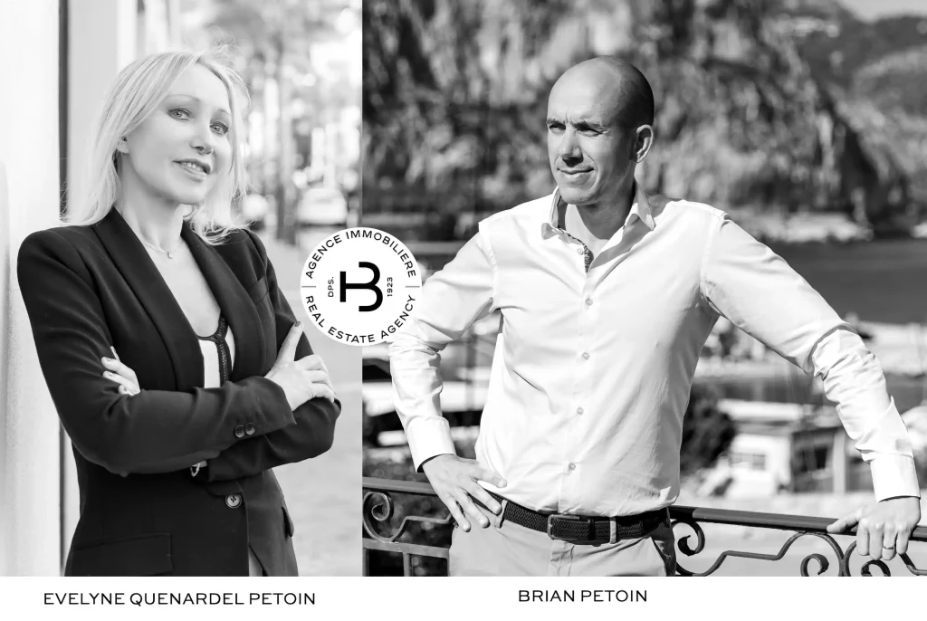 Portrait noir et blanc en diptyque d’une agence immo : à gauche, Evelyne Quenardel Petoin, blonde en blazer sombre, bras croisés, appuyée nonchalamment contre un mur urbain ; à droite, Brian Petoin, chemise claire et crâne rasé, mains sur les hanches, posé contre une balustrade avec vue sur la mer et les collines derrière lui. Au centre, le logo circulaire de l’agence immobilière.