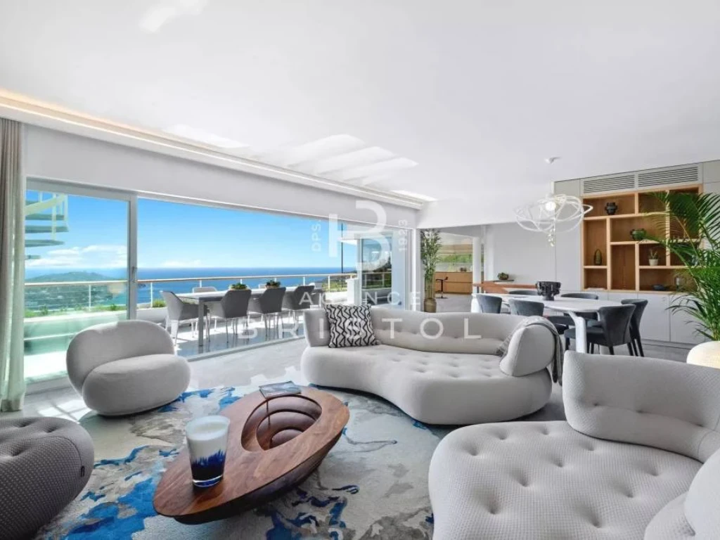 Intérieur lumineux et design avec mobilier haut de gamme, salon spacieux ouvert sur une terrasse avec vue imprenable sur la Méditerranée. Le décor allie élégance moderne et confort, idéal pour un cadre de vie luxueux en bord de mer.