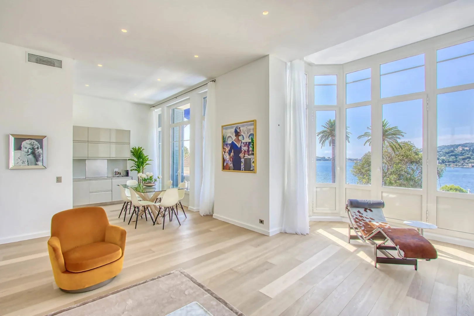 Appartement contemporain avec baie vitrée offrant une vue mer, coin repas design et fauteuils modernes.