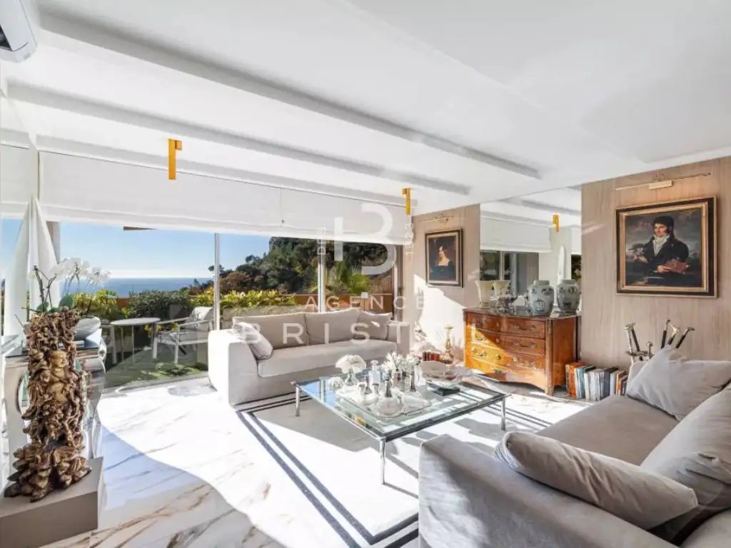 Salon lumineux d’une villa contemporaine à Èze, décoré avec goût dans un style classique et moderne, avec vue sur la mer Méditerranée à travers de grandes baies vitrées.